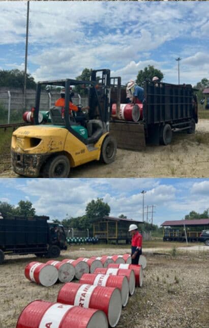 Forklift memindahkan drum pelumas ke atas bak truk di halaman gudang
