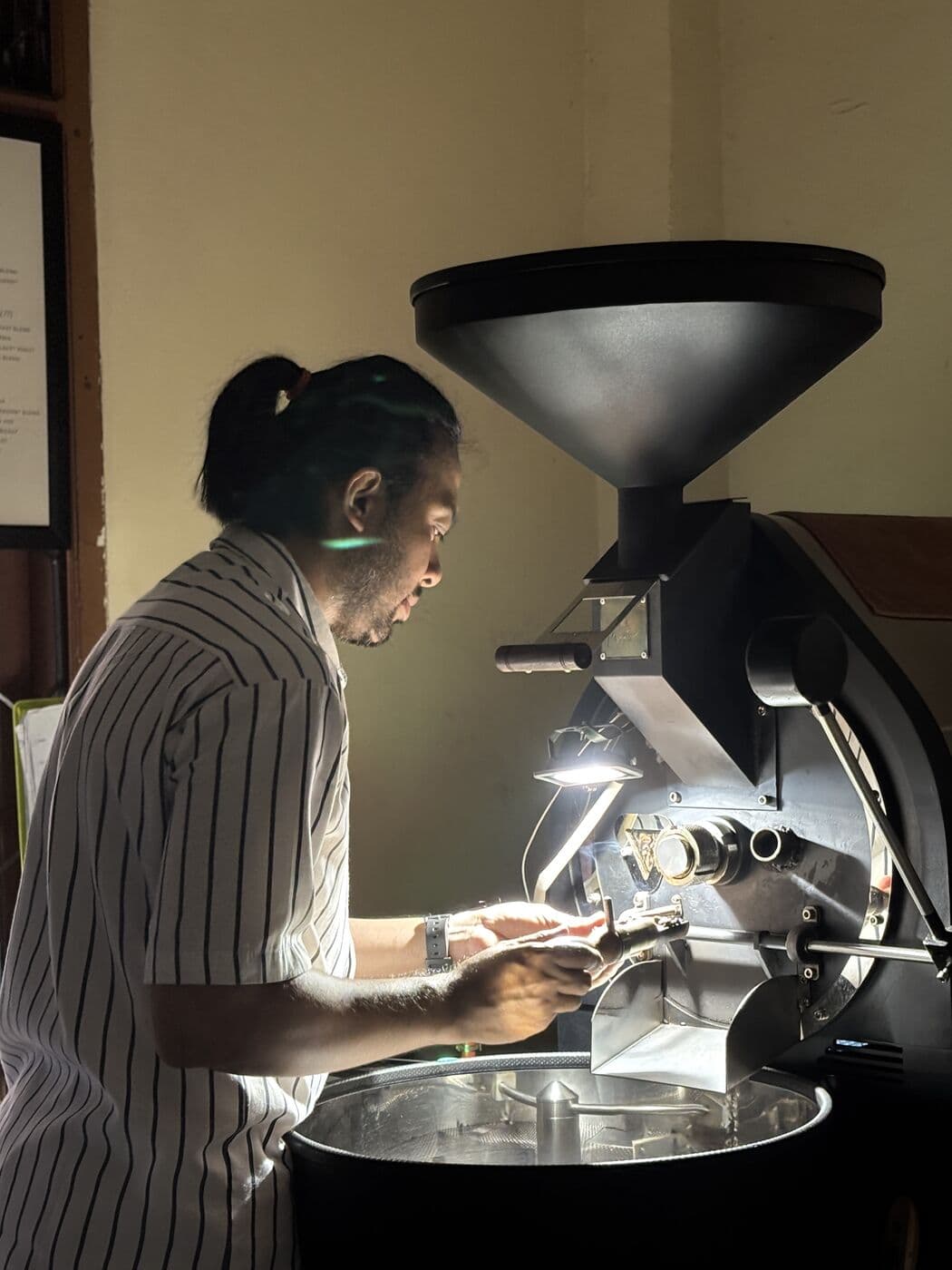 Penyangrai memantau mesin sangrai di roastery Plata Boga